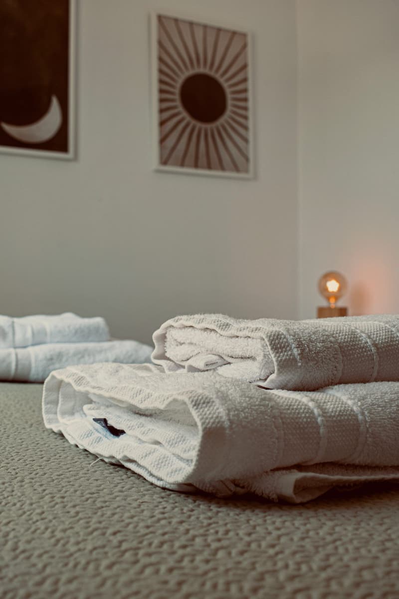 Fresh towels with sun and moon wall art and warm bedside light at Casa dos Amigos